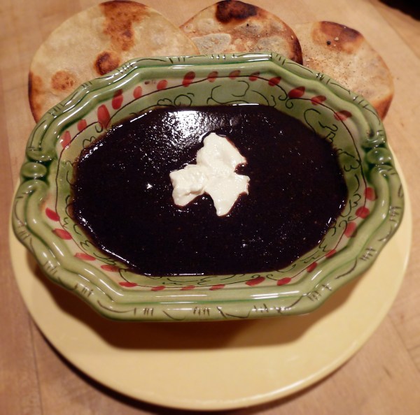 Black bean soup topped with sour cream with a side of spiced fried corn tortillas